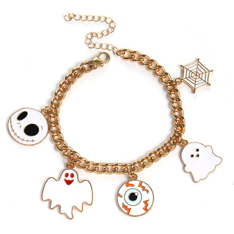 A gold-tone chain bracelet with five Halloween-themed charms: Jack Skellington, a white ghost, a spiderweb, a eyeball with orange lightning bolts, and a small white ghost. The bracelet is photographed on a clean white background.
