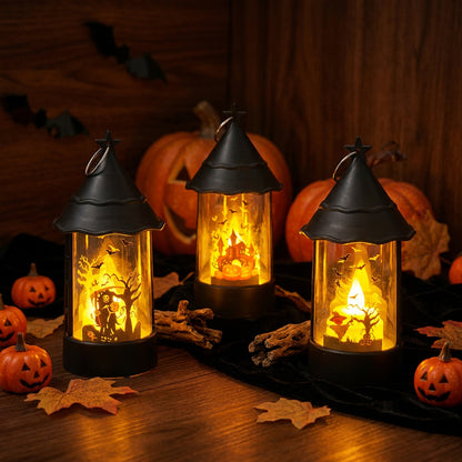Three black metal lanterns with glass sides are lit from within, showing warm orange and yellow fairy lights and spooky silhouettes like trees and bats. They are arranged on a dark cloth on a wooden table with pumpkins, leaves, and bats in the background.