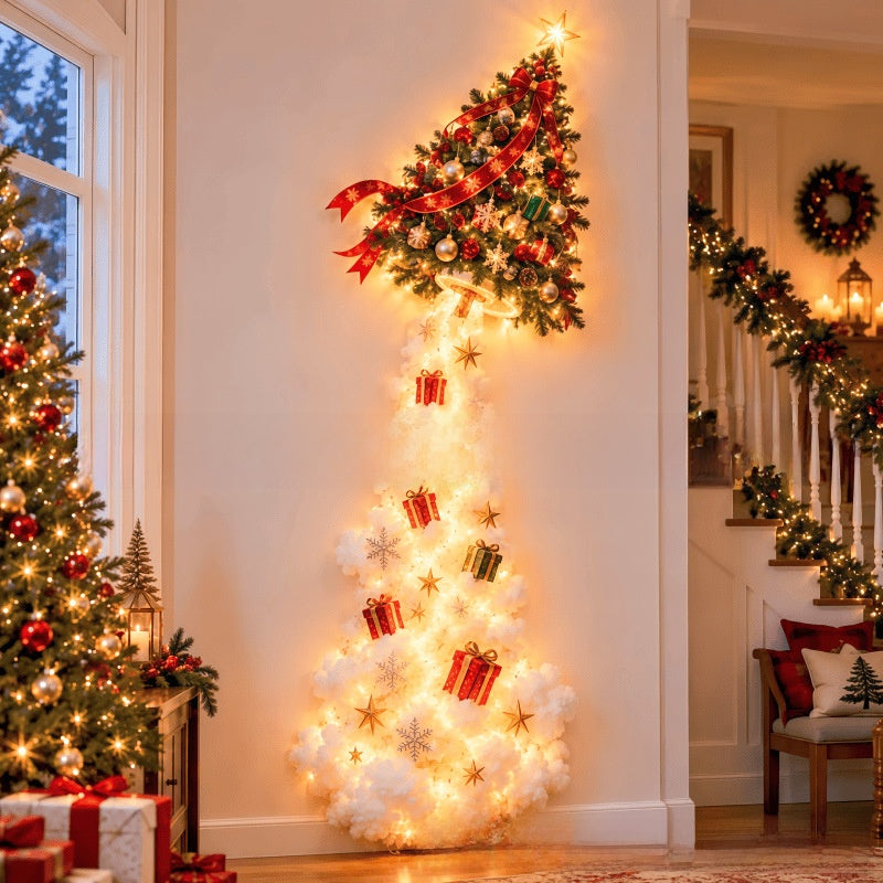 A vertical Christmas tree displayed in a decorated indoor hallway. The tree has a dark green upper section with a red ribbon and star topper, and a white fluffy lower section lit with warm white fairy lights, decorated with red and gold gift boxes and snowflake ornaments.