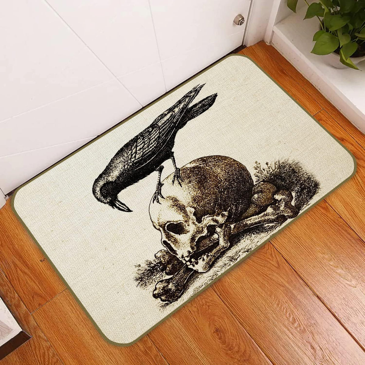 A rectangular doormat with a gothic design featuring a black raven perched on a skull and crossbones, displayed on a wooden floor in front of a white door.