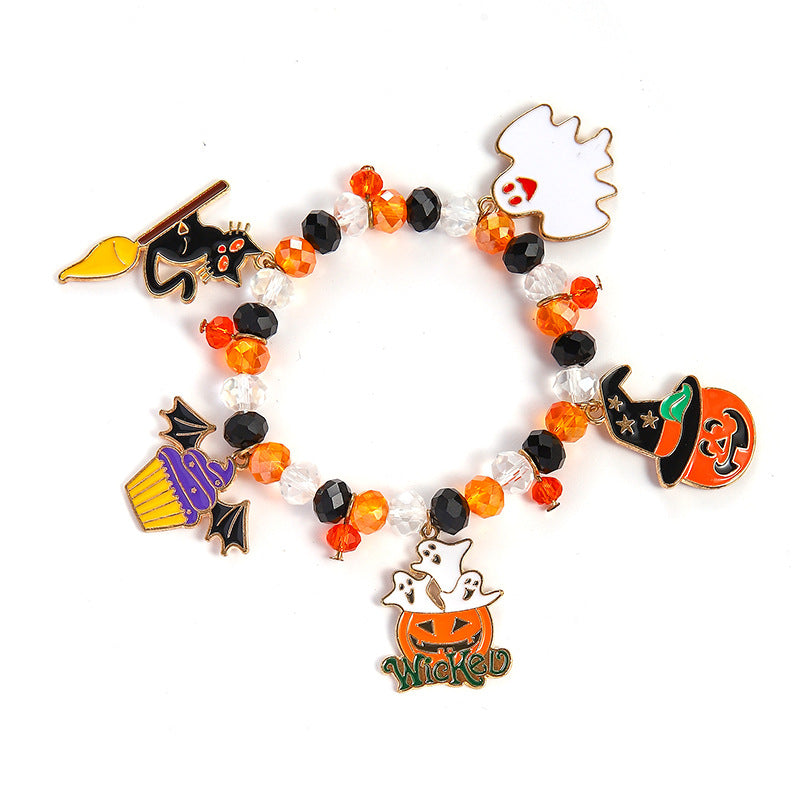 A beaded stretch bracelet with Halloween-themed charms, including a black cat on a broom, a white ghost, an orange pumpkin, a purple cupcake, and a jack-o'-lantern with the word 'Wicked' at the bottom. The bracelet features orange, black, and clear faceted beads on a white background.