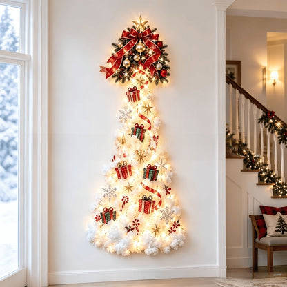 A vertical Christmas tree wall decor piece mounted on a white wall in a home interior. The tree is decorated with warm white string lights, white faux pine needles, red ribbon bows, red gift boxes, candy canes, snowflakes, and gold stars.