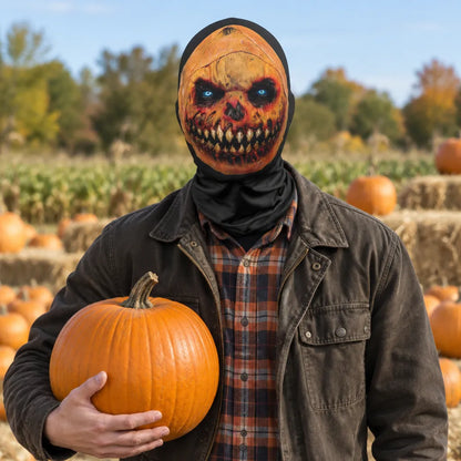A person wearing a black balaclava-style mask with a horror skull face design stands in a pumpkin patch holding a large orange pumpkin. The person is also wearing a dark brown jacket over a brown and red plaid shirt.