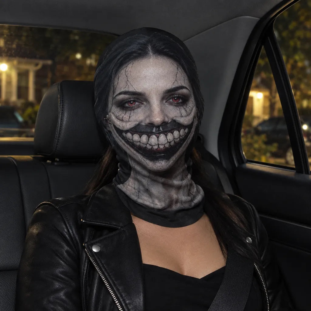 A person sitting in a car wearing a creepy, horror-style makeup look with a wide black grin, cracked pale face paint, and a black neck gaiter, along with a black leather jacket.